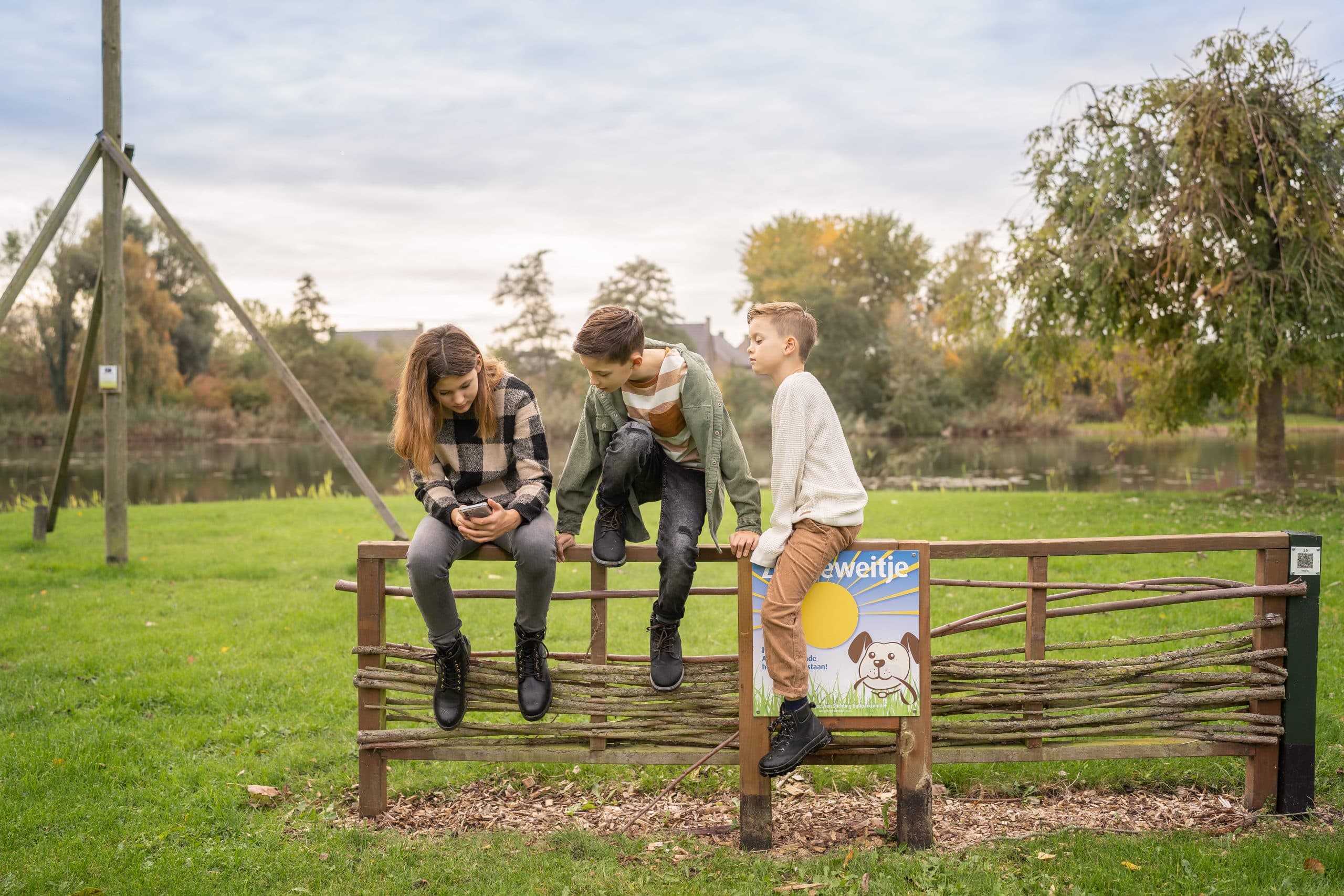 Kinderen op een hek die kijken naar een mobieltje. Kinderalimentatie hulp nodig? Bmiddl.nl helpt daarbij.